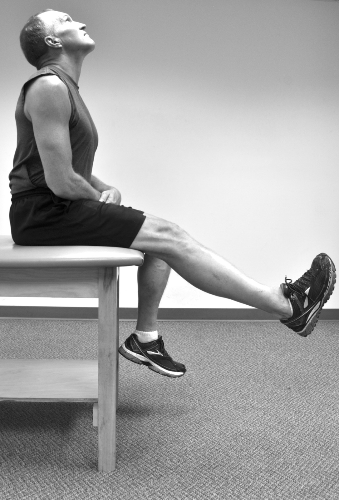 Person seated on a bench while extending one leg forward.